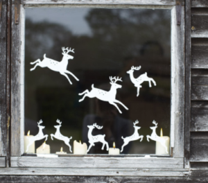 Simple white decals of Christmas reindeer on a window